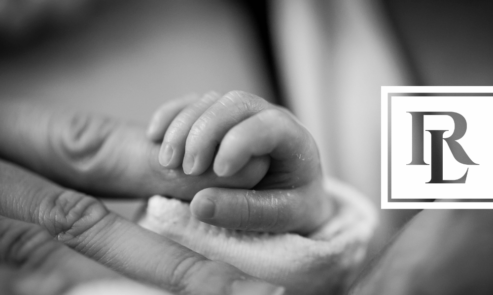 Close-up of adult hand holding newborn baby's hand