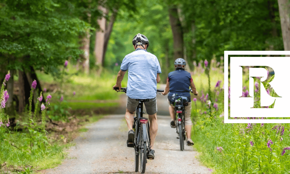 Two individuals biking down a dirt path