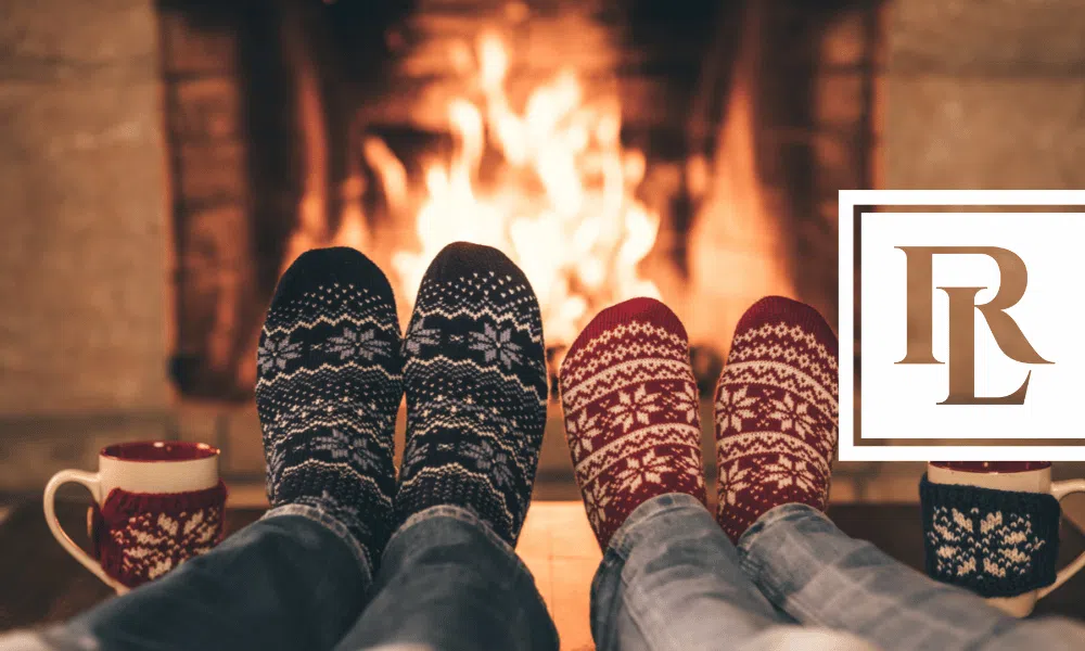 Two people placing their sock covered feet in front of a fireplace