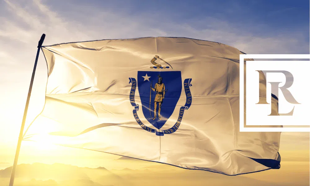 Massachusetts state flag waving in the wind with the sun shining through.